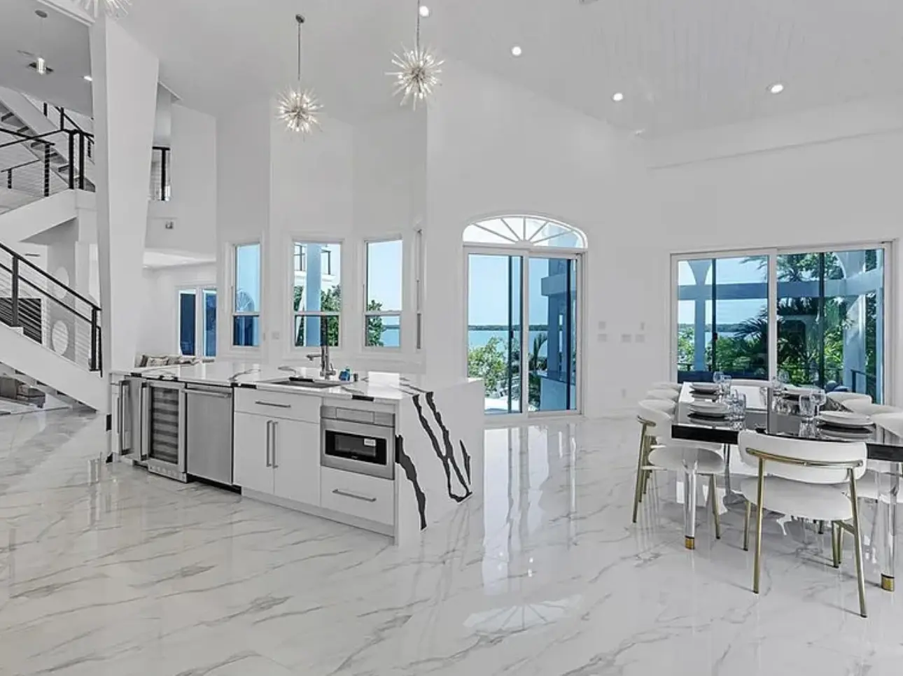 Renovated kitchen and dining area with white cabinetry and polished flooring