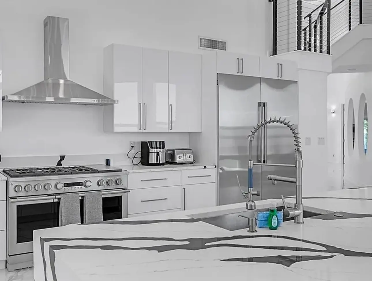 Waterfront whole-home renovation kitchen with white cabinets and stone surfaces