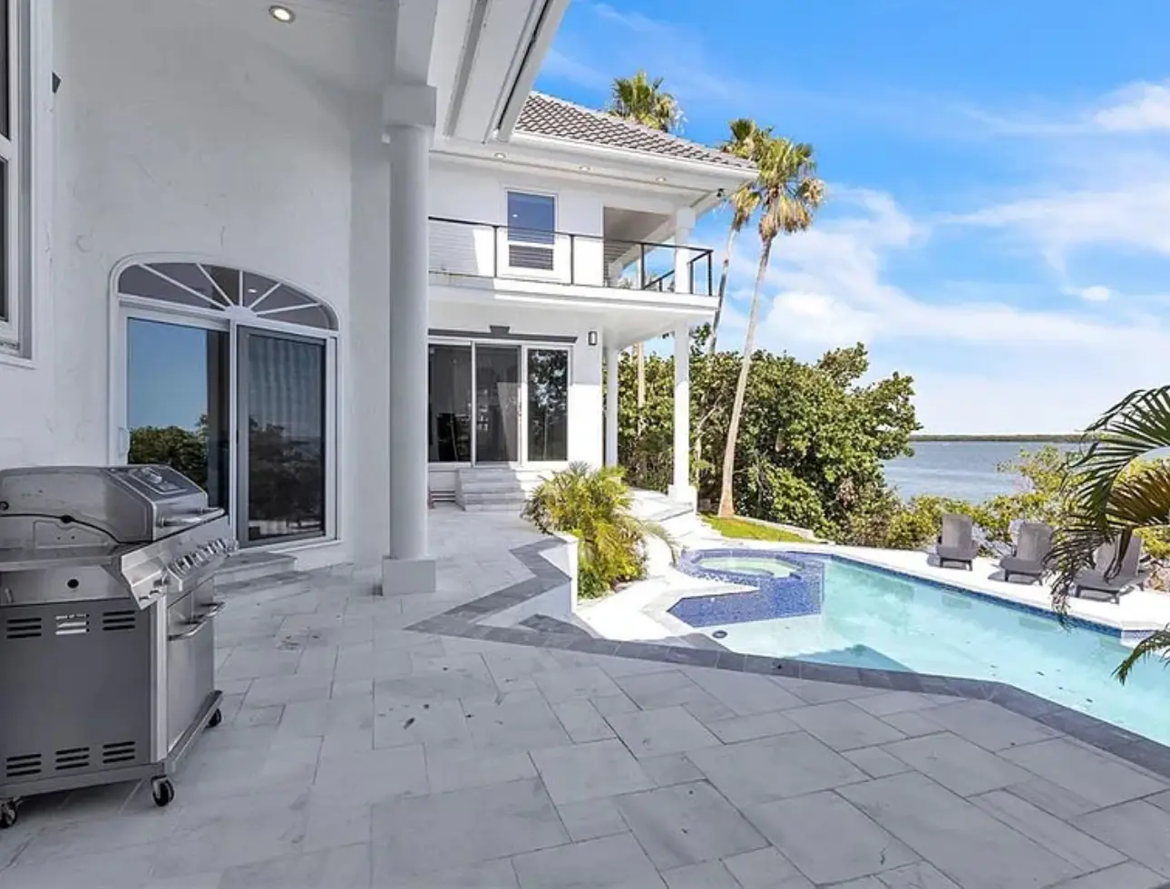 Waterfront outdoor living and pool area connected to the renovated home