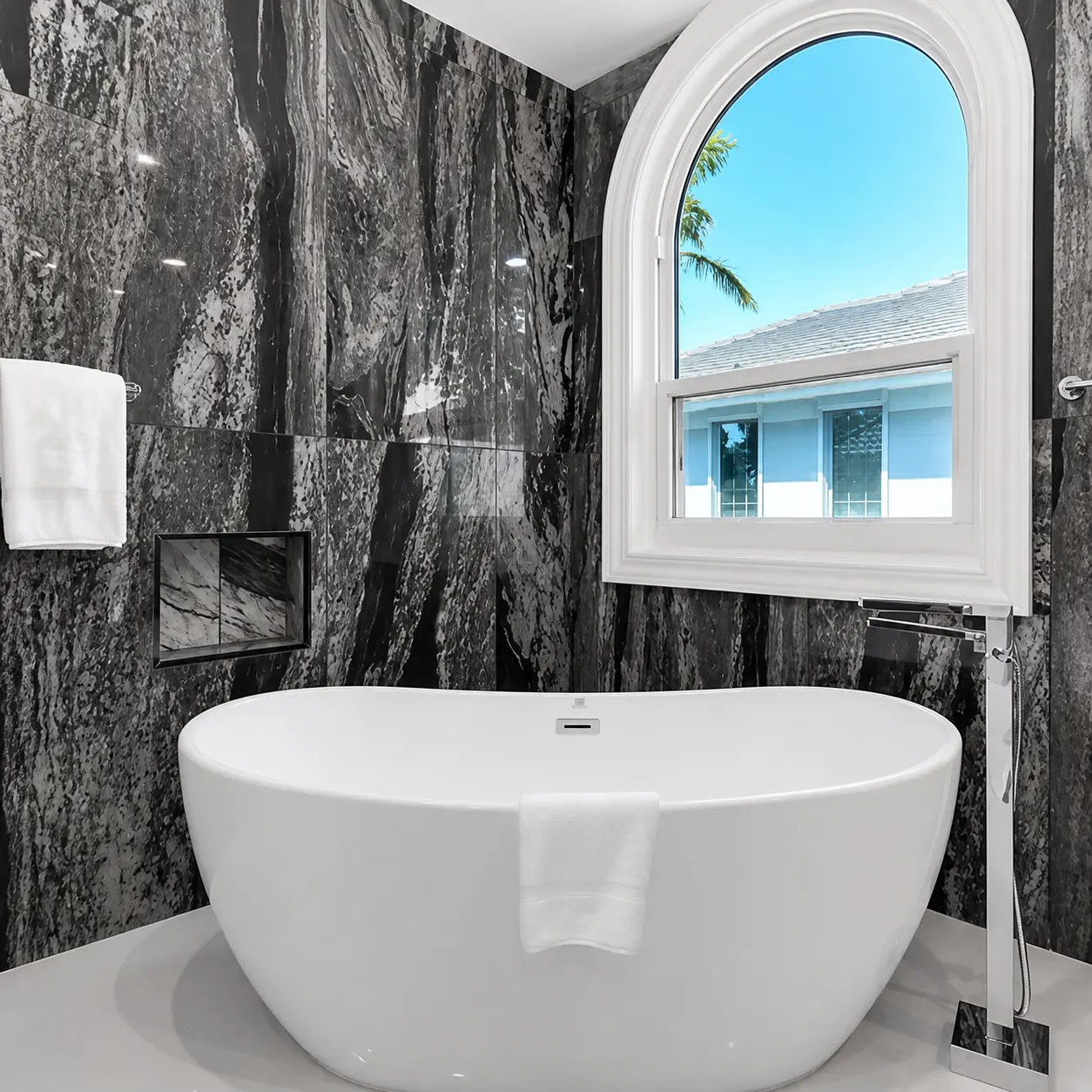 Completed Tampa primary bathroom with a freestanding tub and marble-look wall